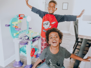 Two boys enjoying a playful moment together with a new toy in the background.